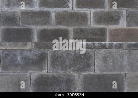 Abstract architectural background showing gray concrete masonry blocks arranged in horizontal rows with weathered surface texture Stock Photo