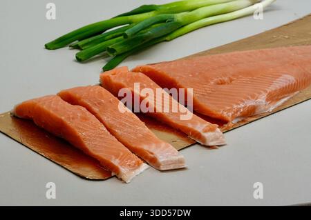 salmon fillet on cutting board with green onions on white background Stock Photo