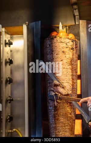 Close-up of a chef slicing traditional Turkish doner kebab meat from a vertical rotisserie Stock Photo