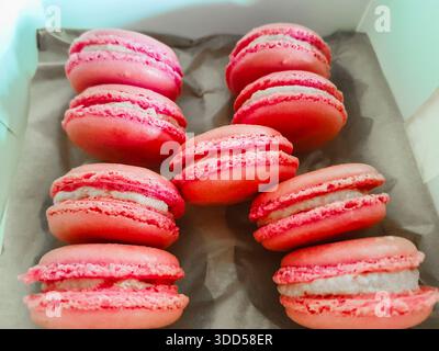 Box containing a number of pink macaroons with cream filling. Stock Photo
