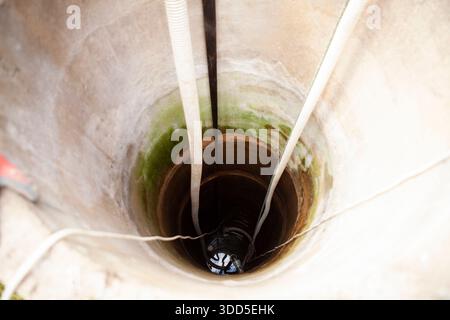 Cleaning a rural concrete well: The first stage involves pumping out all the water to the very bottom. This allows access to the well s base for thoro Stock Photo