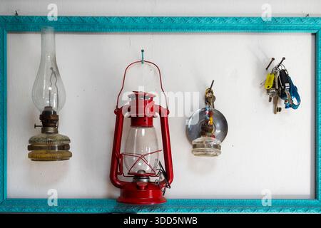A collection of vintage kerosene lamps and keys hanging inside a decorative turquoise frame on a white wall in Nazareth, Israel. Stock Photo