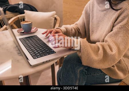 Woman freelancer working on laptop with coffee Stock Photo