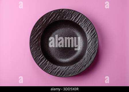 An empty round ceramic plate on a pink background as a kitchen utensil. An empty plate as a food background for your design Stock Photo