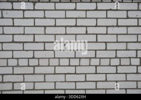 White painted brick wall texture background, a seamless pattern of an old and weathered exterior facade. Close-up view of the masonry surface. Stock Photo