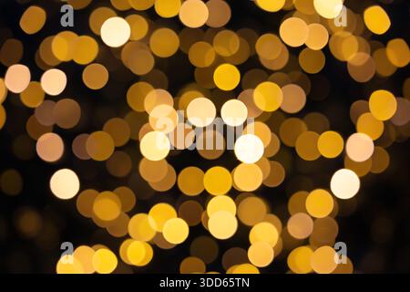Flashing yellow Christmas lights and bokeh from the blur. Dark background. Stock Photo