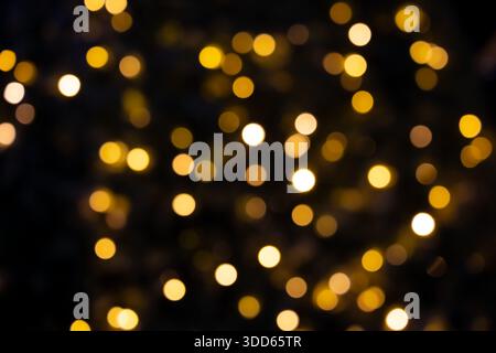 Flashing yellow Christmas lights and bokeh from the blur. Dark background. Stock Photo