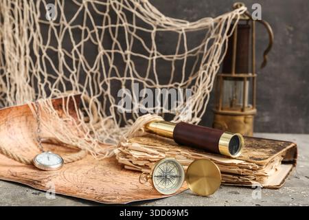 Golden compass, world map, net, spyglass and old book on grey grunge background Stock Photo