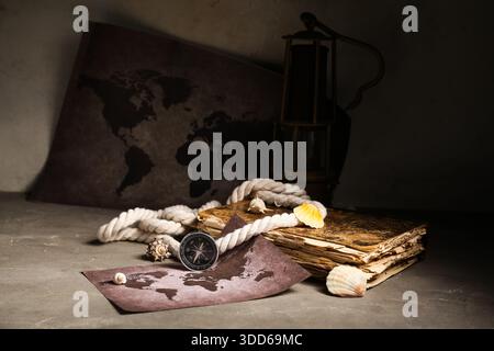 Composition with modern compass, world map, old book, rope and seashells on grey grunge background Stock Photo