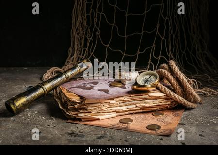 Composition with golden vintage compass, rope, old book, map and spyglass on grey grunge background Stock Photo