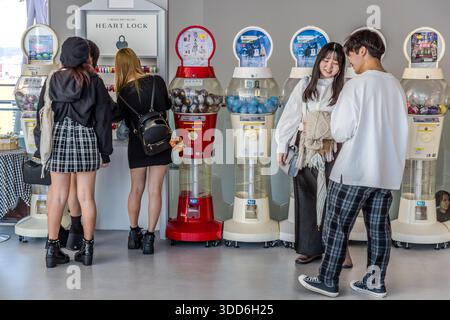 Three young women and a couple stand in front of vending machines in the Umeda Sky Building. Osaka, Osaka Prefecture, Japan Stock Photo