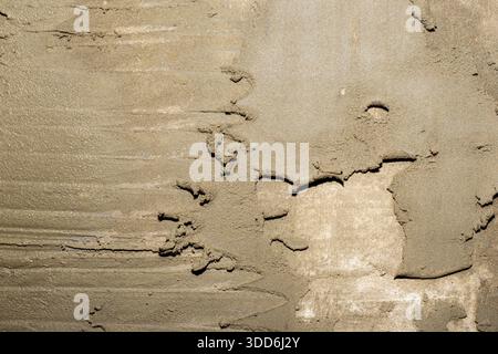 A raw, damp cement or plaster surface shows pronounced trowel marks and an uneven, textured finish, ideal for construction or renovation. Stock Photo