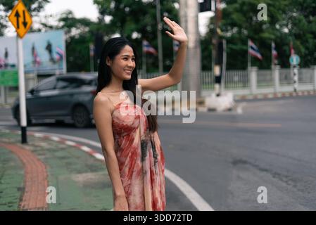 Smiling asian woman waving hand, greeting on urban street with friendly expression Stock Photo