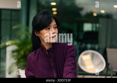 Asian woman in purple jacket looking right, urban lifestyle and calm expression Stock Photo