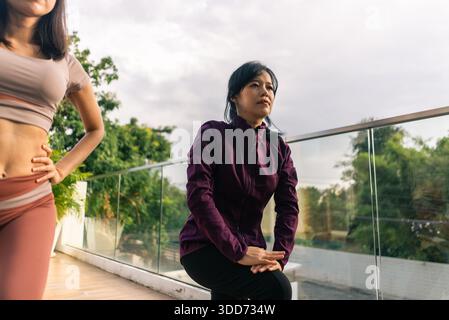 Asian women training together, doing outdoor exercises and sport stretching Stock Photo