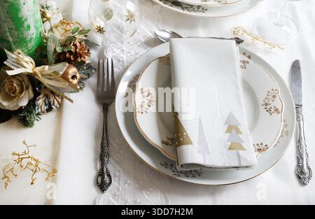 Elegant and festive setting, perfect for the Christmas table, with white, gold and silver-grey colors. Christmas decorations with baubles, candle. Stock Photo
