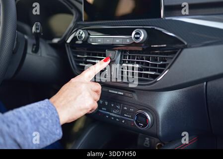 Female pressing red triangle car hazard warning button Stock Photo