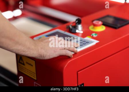 Hand on the control panel of automated industrial machinery. Machine operator push button on the control panel of automated industrial laser cutting a Stock Photo