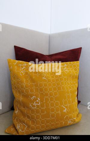 A stylish corner of a modern living room featuring a yellow patterned pillow and a plush white sofa. Stock Photo