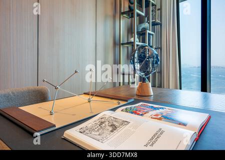 Modern luxury office interior with executive desk, armillary globe, molecular model and open architecture book, featuring floor-to-ceiling window. Stock Photo
