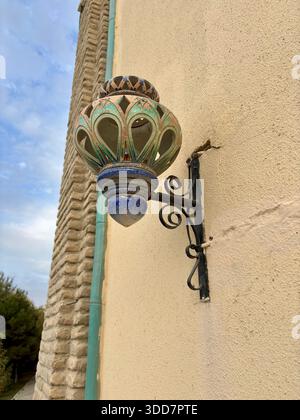 Ornate ceramic wall lantern on an ancient brick and plaster building Stock Photo