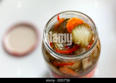 An open jar of cucumbers, carrots and peppers in brine, top view Stock Photo