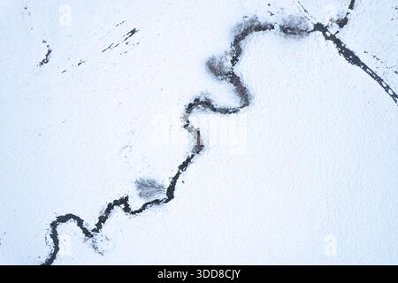 Contrast of a Dark Stream on a Pure White Snowfield Stock Photo