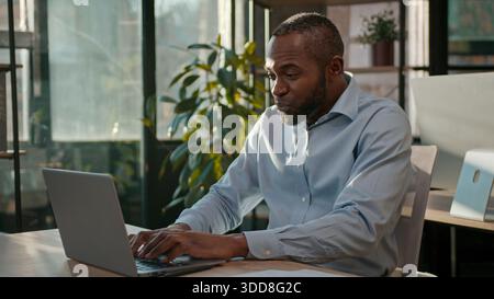 African American 40s business man typing laptop web service cyberspace adult businessman working online at office smiling mature male executive worker Stock Photo
