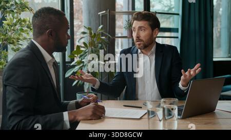 Two diverse business men team multiracial businessmen emotional talking discuss problem negotiation stress job partnership in office discussing ideas Stock Photo