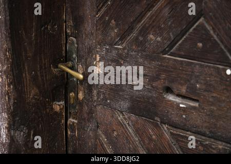 Close-up of Old Wooden Door with Yellow Metal Handle Stock Photo