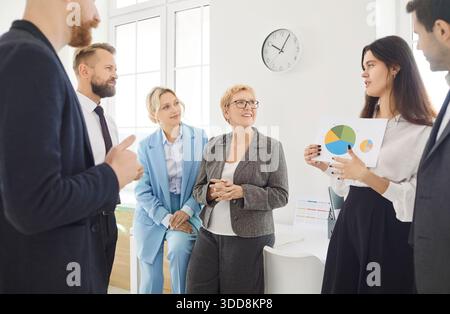 People standing in office during business team meeting analyzing financial pie chart, statistics Stock Photo