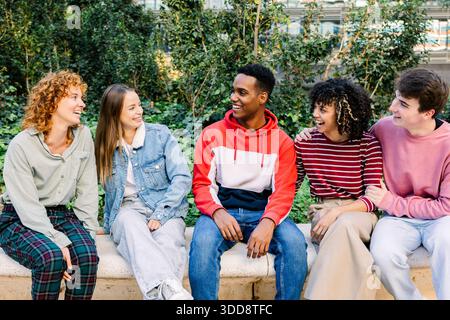 Group of diverse smiling young friends interacting outdoors Stock Photo