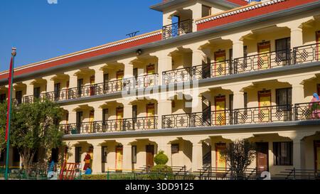 Modern yellow building with symmetrical design, multiple levels, and balconies, showcasing a clean and structured architectural style. Stock Photo
