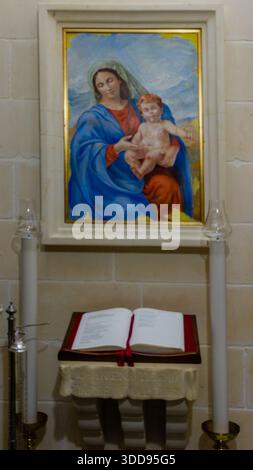 Religious Artwork of Mary With Child Jesus Above Open Bible on Altar in Chapel Setting Stock Photo