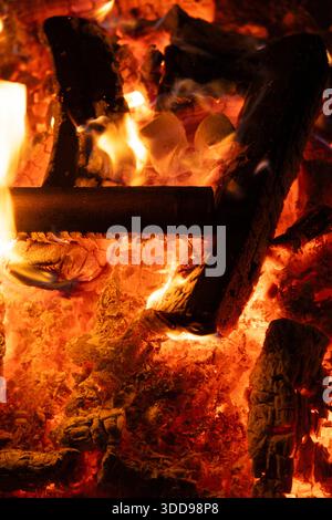 Warm Campfire with Glowing Coals and Wooden Logs at Night. Stock Photo
