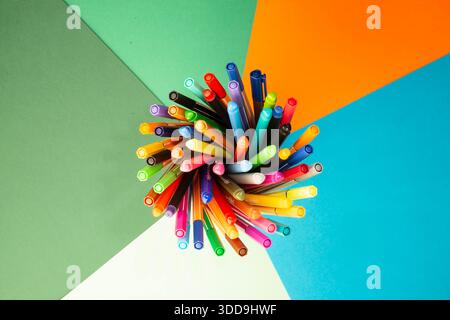 Creative workspace concept with multicolored pens arranged in a radial pattern, representing innovation, teamwork, and strategic thinking Stock Photo