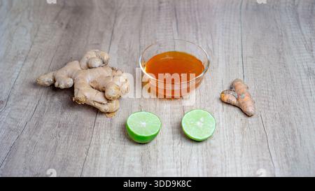 Flat lay of ginger, lime, turmeric, and honey on wooden surface Stock Photo