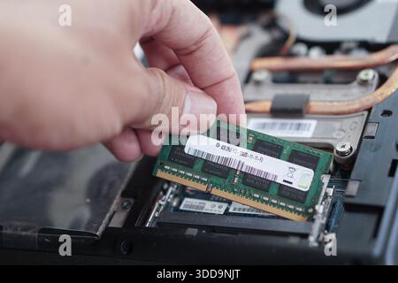 Action shot of a computer technician replacing a faulty or old RAM module in a laptop. Essential step in hardware troubleshooting. Stock Photo