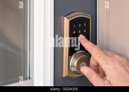 Closeup of a hand pressing buttons to enter a security code on a residential home door lock keypad Stock Photo