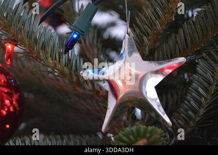 Silver Star Ornament Hanging on a Decorated Christmas Tree Stock Photo