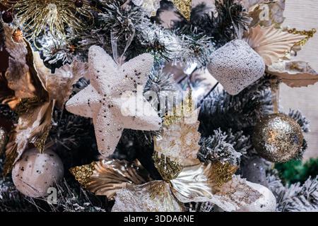 Christmas tree decorations of various shapes hang on a decorated Christmas tree. Stock Photo