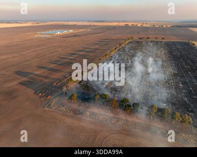 Aerial view of long shadows and smoke clouds rising from burning farmland at Moolort in Central Victoria, Australia Stock Photo