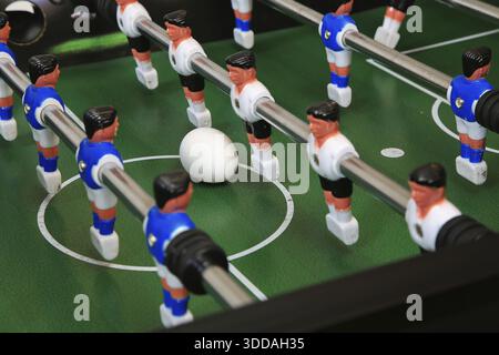 Close-up table football design On the green playing area with white lines, there is not a ball, but an egg, surrounded by mounted plastic players on m Stock Photo