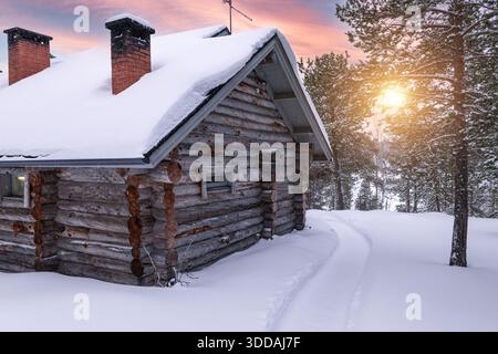 Scandinavian Log Cabin Covered with Snow in the Forest at Sunset in Winter Stock Photo