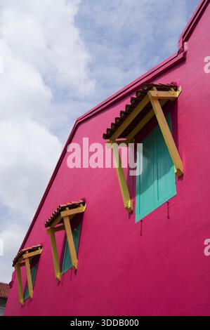Cropped shot of some windows on a pink wall, against a clear blue sky. Stock Photo