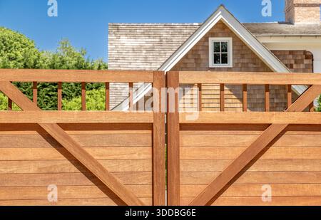 closeup image of a brand new mahogany gate with part of a house just beyond Stock Photo
