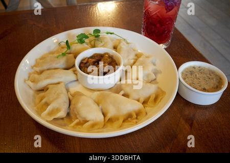 bowl of pierogi perogies traditional dumplings with onion and fried bacon and mushroom dips in pierogarnia mandu gdansk poland Stock Photo