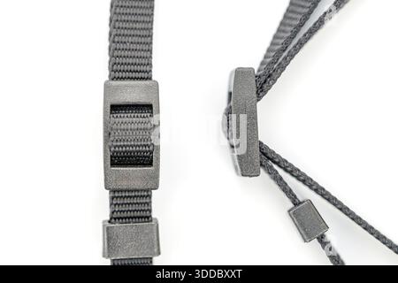 A close-up shows two adjustable black nylon straps with plastic adjusters against a white background. One is flat webbing, and the other is corded. Th Stock Photo