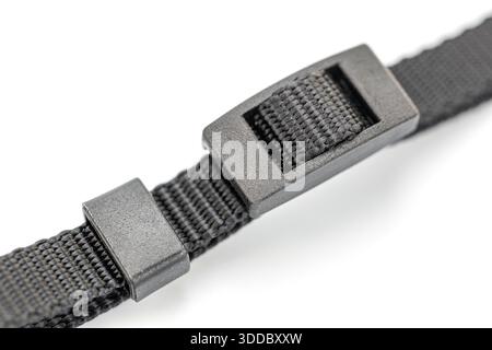A close-up shot showcases a black nylon strap, featuring a plastic buckle. The rough texture of the woven nylon contrasts with the smooth, matte finis Stock Photo