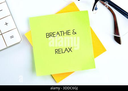 A gentle reminder graces a workspace. Colorful notes stating Breathe Relax rest near a calculator and spectacles, creating a calm and organized atmosp Stock Photo